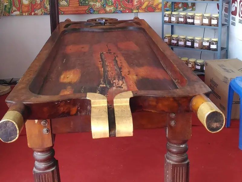 A traditional wooden Ayurvedic massage table (droni) used for oil therapies