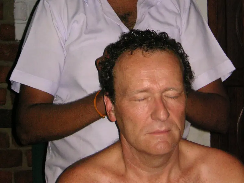 A therapist giving a seated Ayurvedic head massage